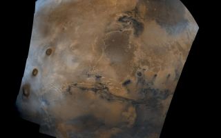 <h1>PIA00003:  Valles Marineris Hemisphere</h1><div class="PIA00003" lang="en" style="width:800px;text-align:left;margin:auto;background-color:#000;padding:10px;max-height:150px;overflow:auto;">Mosaic composed of 102 Viking Orbiter images of Mars, covering nearly a full hemisphere of the planet (approximate latitude -55 to 60 degrees, longitude 30 to 130 degrees). The mosaic is in a point-perspective projection with a scale of about 1 km/pixel. The color variations have been enhanced by a factor of about two, and the large-scale brightness variations (mostly due to sun-angle variations) have been normalized by large-scale filtering. The center of the scene shows the entire Valles Marineris canyon system, over 3,000 km long and up to 8 km deep, extending from Noctis Labyrinthus, the arcuate system of graben to the west, to the chaotic terrain to the east. Bright white layers of material in the eastern canyons may consist of carbonates deposited in ancient lakes. Huge ancient river channels begin from the chaotic terrain and from north-central canyons and run north. Many of the channels flowed into a basin called Acidalia Planitia, which is the dark area in the extreme north of this picture. The Viking 1 landing site (Mutch Memorial Station) is located in Chryse Planitia, south of Acidalia Planitia. The three Tharsis volcanoes (dark red spots), each about 25 km high, are visible to the west. The large crater with two prominent rings located at the bottom of this image is named Lowell, after the Flagstaff astronomer. The images were acquired by Viking Orbiter 1 in 1980 during early northern summer on Mars (Ls = 70 degrees); the atmosphere was relatively dust-free. A variety of clouds appear as bright blue streaks and hazes, and probably consist of water ice. Long, linear clouds north of central Valles Marineris appear to emanate from impact craters.<br /><br /><a href="http://photojournal.jpl.nasa.gov/catalog/PIA00003" onclick="window.open(this.href); return false;" title="Voir l'image 	 PIA00003:  Valles Marineris Hemisphere	  sur le site de la NASA">Voir l'image 	 PIA00003:  Valles Marineris Hemisphere	  sur le site de la NASA.</a></div>